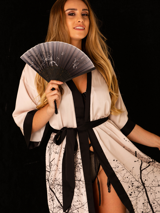 Ein Model posiert in einem traditionellen Kimono im japanischen Stil. Der Kimono ist mit detaillierten Mustern und leuchtenden Farben verziert, die die kulturelle Ästhetik Japans widerspiegeln. Das Outfit wird durch einen eleganten Obi-Gürtel komplettiert, der die Taille betont. Der Hintergrund ist dezent gehalten, um den Fokus auf die kunstvollen Details des Kimonos zu legen.